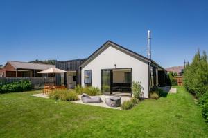 Northlake Hideaway - Wanaka Holiday Home في واناكا: منزل أبيض مع ساحة خضراء