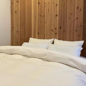 een groot bed met witte lakens en kussens bij Hostel Mt. Fuji - FUKUYA in Fujiyoshida