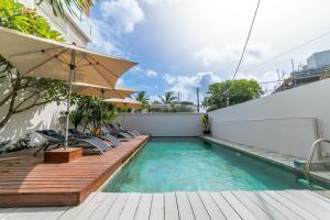 a swimming pool with chairs and an umbrella at Beachcove Apartment 9 in Pereybere in Pereybere