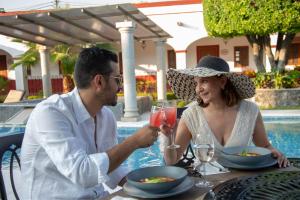 Ein Mann und eine Frau sitzen mit einem Drink an einem Tisch. in der Unterkunft Ex Hacienda Santa Cecilia in Cuernavaca