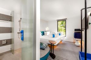 a room with a bed and a bathroom with a shower at COSI Samui Chaweng Beach - SHA Plus in Chaweng