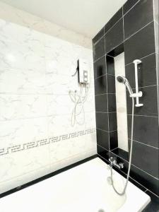 a shower in a bathroom with black and white tiles at Keen's Smiley Homestay in Phnom Penh