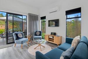 a living room with a blue couch and two chairs at Kotuku Apartment - Kaiteriteri Holiday Unit in Kaiteriteri