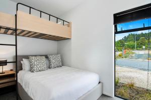 a bedroom with a bunk bed and a large window at Kotuku Apartment - Kaiteriteri Holiday Unit in Kaiteriteri
