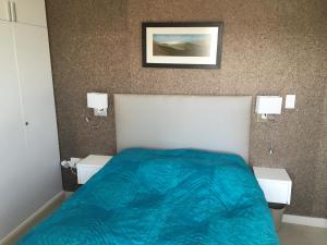 a bedroom with a bed with a blue blanket on it at Ocean view, Swakopmund, 3-bedroomed apartment in Swakopmund