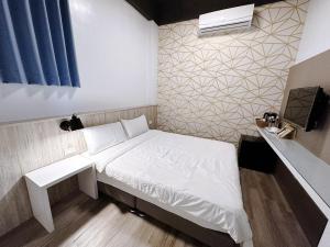 een kleine slaapkamer met een wit bed en een raam bij Starrywhale hostel in Magong