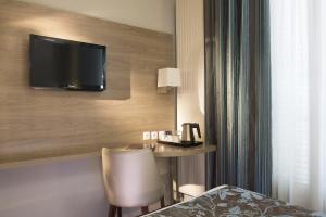 a hotel room with a desk and a television on the wall at Turenne Le Marais in Paris