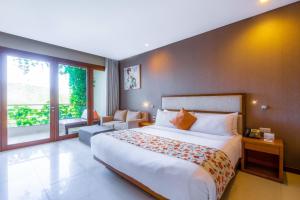 a bedroom with a large bed and a large window at VOUK Hotel and Suites Nusa Dua Bali in Nusa Dua