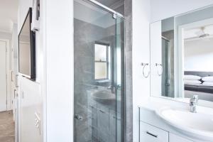 Baño blanco con lavabo y espejo en NRMA Jindabyne Holiday Park, en Jindabyne