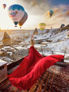 a woman laying on a roof looking at hot air balloons at Naraca Cave House in Göreme