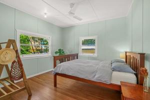 a bedroom with a bed and a table and two windows at Dougys Beach Shack in Kingscliff