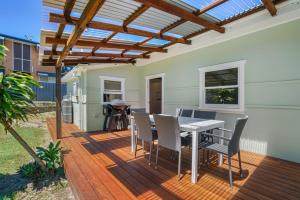 a patio with a table and chairs on a deck at Dougys Beach Shack in Kingscliff