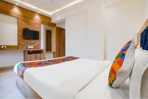1 dormitorio con 1 cama blanca y TV en FabHotel Pancharatna Regency en Pune