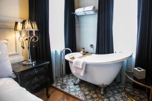 ein Bad mit einer Badewanne in einem Zimmer mit einem Bett in der Unterkunft Hotel Australasia in Eden