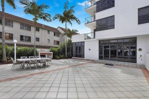 un patio con mesas y sillas frente a un edificio en Aqualine Apartments On The Broadwater, en Gold Coast