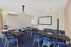 une salle de classe avec des tables et des chaises et un mur blanc dans l'établissement Aqualine Apartments On The Broadwater, à Gold Coast