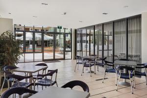 una cafetería con mesas, sillas y ventanas en Aqualine Apartments On The Broadwater, en Gold Coast