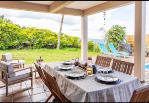 a table and chairs on a patio with a view of the ocean at Au Bois Bichette in La Possession