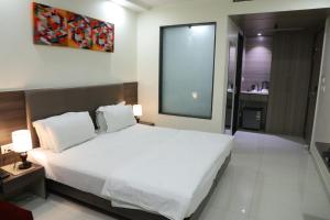 a bedroom with a large white bed and a bathroom at Hotel Sopan Heights in New Delhi