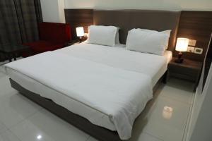 - un grand lit blanc dans une chambre d'hôtel dans l'établissement Hotel Sopan Heights, à New Delhi