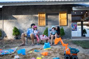 une famille assise sur une chaise dans le sable dans l'établissement Tararom ธาราลม, 