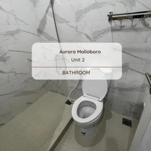 La salle de bains est pourvue de toilettes blanches avec un panneau. dans l'établissement HOMESTAY AURORA, à Ngabean