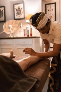 Um homem está a depilar a perna de um homem num sofá. em Hotel & Spa Pałac Mała Wieś em Mała Wieś