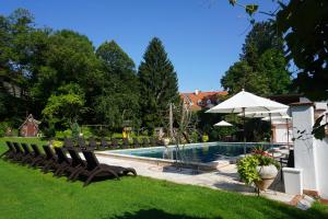 a swimming pool in a yard with chairs and an umbrella at Gartenhotel Kloepferkeller in Eibiswald