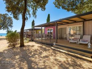 a house with a deck with chairs and a tree at Mobile Home Pag near Pebble Beach & Pools in Novalja