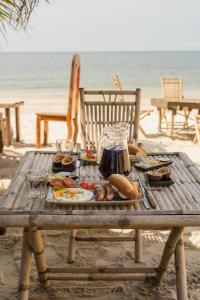 un tavolo da picnic sulla spiaggia con cibo di Young Wild and Free a Koh Kong