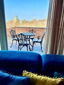 a blue couch in front of a window with a table and chairs at Penthouse Apartment 401 in Tbilisi City