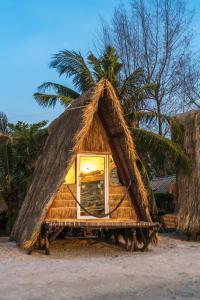 a small hut on the beach with a palm tree at Young Wild and Free in Koh Kong