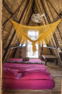 a bed in a thatched room with a ceiling at Young Wild and Free in Koh Kong