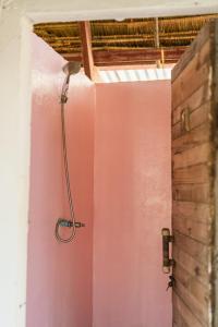 eine Dusche in einem Zimmer mit einer rosa Wand in der Unterkunft Young Wild and Free in Koh Kong