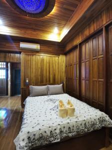 a bedroom with a bed with two yellow shoes on it at Thai traditional wooden house in Ban Nong Bu