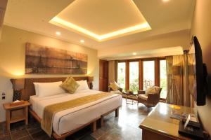 a hotel room with a bed and a desk and windows at Puri Raja Hotel in Legian