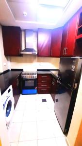 cocina con armarios de madera, lavadora y secadora en Stufio flat DG085, Close to The Gardens Metro 6 min walkable, en Dubái
