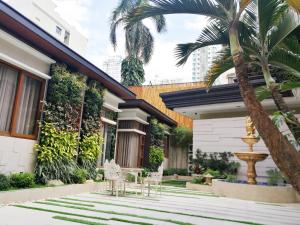 Adria Residences - Ruby Garden - 2 Bedroom for 4 person في مانيلا: منزل به ساحة مع كراسي ونافورة