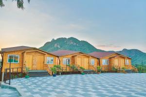 una fila de lodges de madera con montañas en el fondo en Bamboo Saa Resort & Spa - Udaipur, en Udaipur