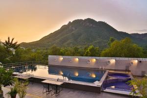 un complejo con una piscina con una montaña en el fondo en Bamboo Saa Resort & Spa - Udaipur, en Udaipur