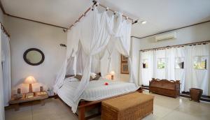a bedroom with a canopy bed with white drapes at Visakha Sanur in Sanur