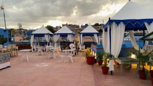 a rooftop patio with tables and white chairs and umbrellas at Rani Mahal in Jodhpur