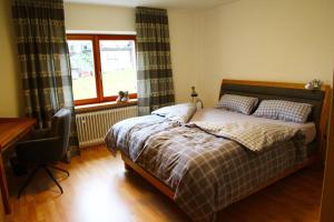 a bedroom with a bed and a desk and a window at Bergsonne in Reit im Winkl