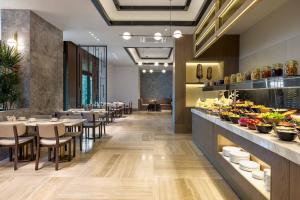 a dining room with tables and chairs and a buffet at Movenpick Living Istanbul Camlivadi in Istanbul