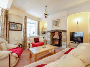 a living room with couches and a fireplace at Harvey Cottage in Colyton