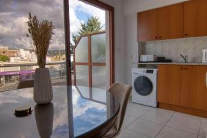 een keuken met een glazen tafel en een wasmachine bij Phaedrus Living: City Flat Palas 102 in Paphos City