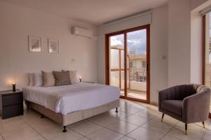 een slaapkamer met een bed, een stoel en een raam bij Phaedrus Living: City Flat Palas 102 in Paphos City