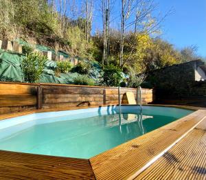 una piscina en un jardín con terraza de madera en Le SPA de l’Abbaye, en Saint-Junien