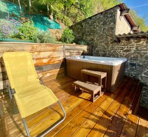 una silla y una bañera en una terraza de madera en Le SPA de l’Abbaye, en Saint-Junien