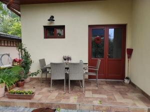 a patio with a table and chairs and a red door at Eleonóra Villa in Balatonlelle